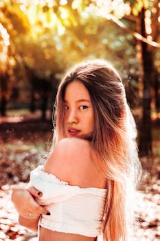 Captivating portrait of a woman in a sunlit autumn forest evoking warmth and mystery.