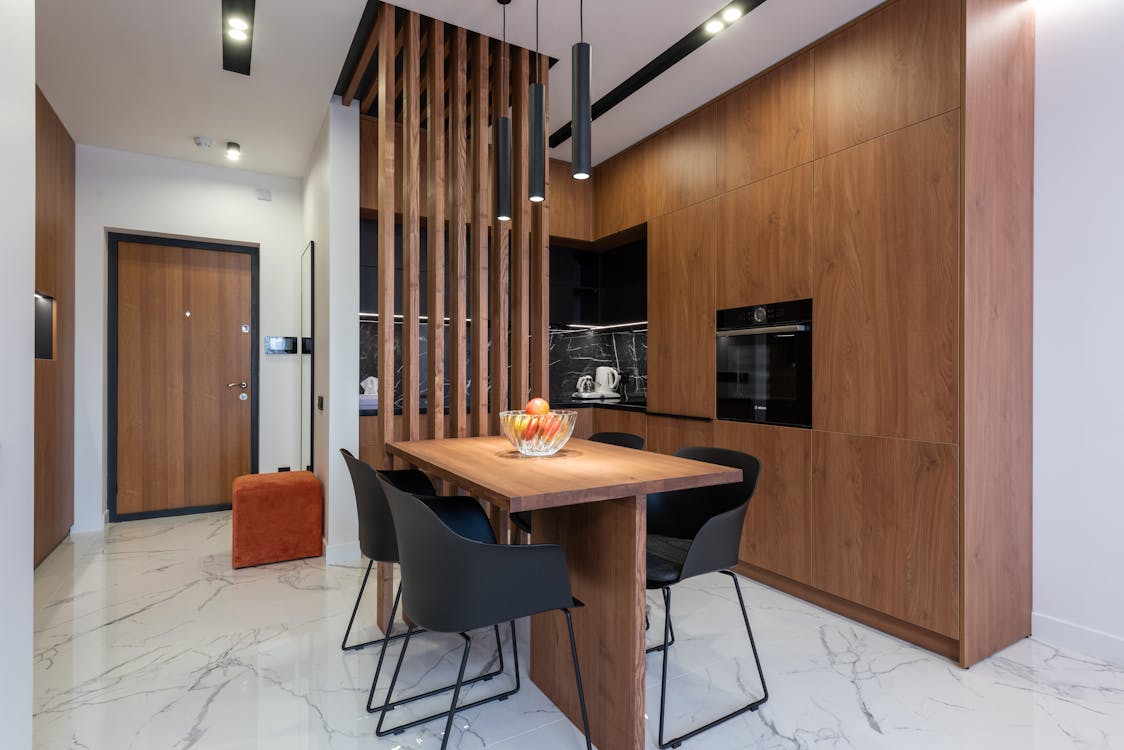 Dining area in modern kitchen with stylish wooden furniture and appliances decorated with creative lamps