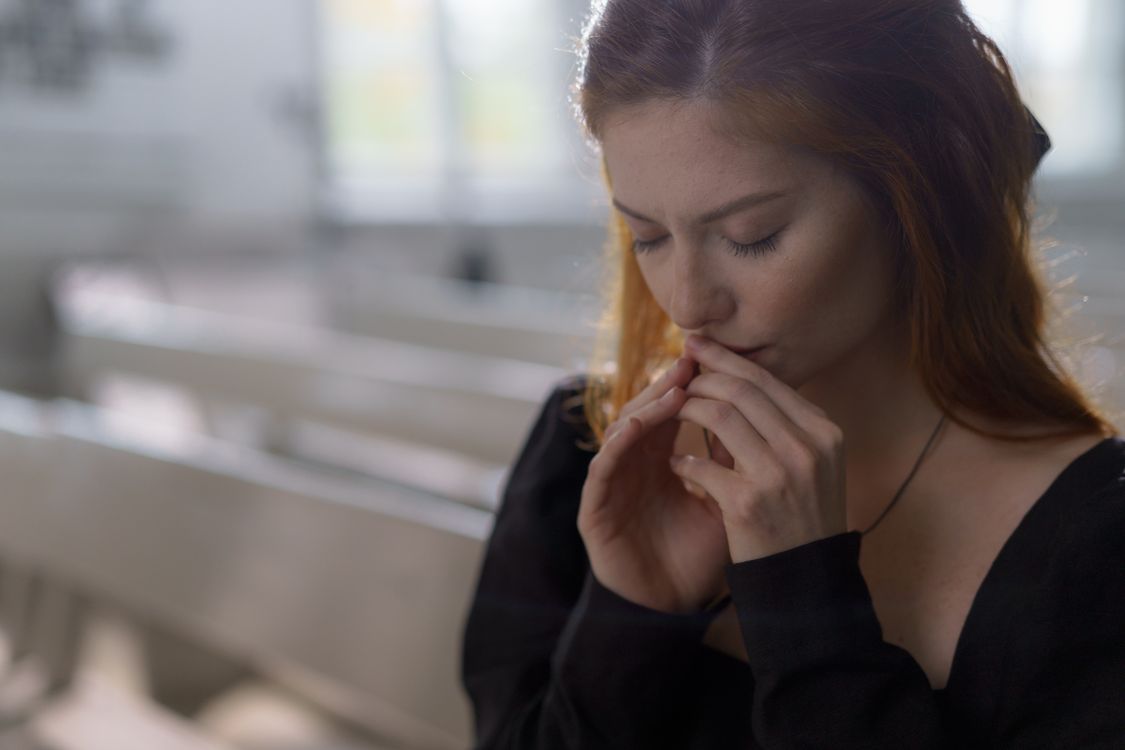 Woman with eyes closed and hands clasped in prayer, reflecting dependence on Yahawah and spiritual growth