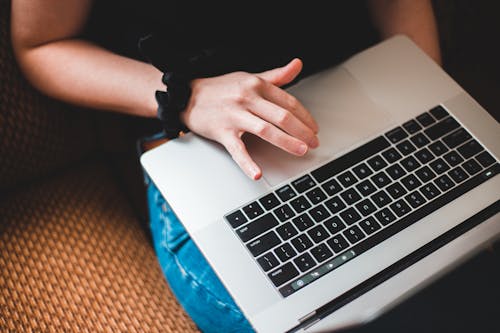 Free Crop freelancer working on laptop on sofa Stock Photo