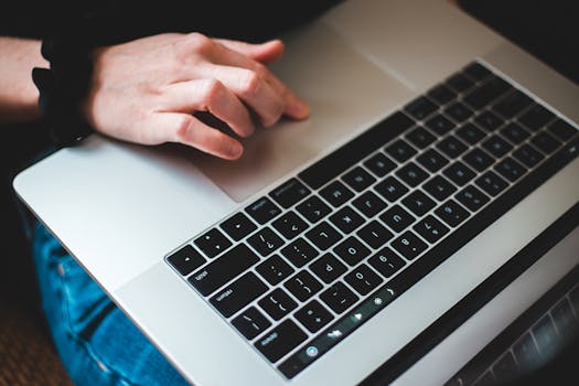 Person typing on a laptop keyboard, focusing on hands and modern technology usage.