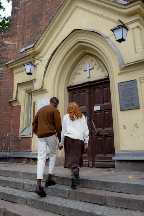 Мужчина и женщина, стоящие перед коричневой деревянной дверью
