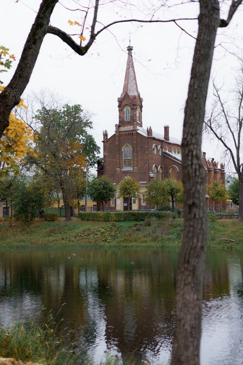 Free Gothic church by a calm river with autumn foliage and reflections. Stock Photo