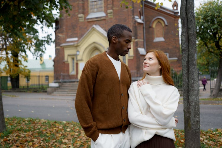 Man In Brown Cardigan Standing Beside A Woman In White Knitted Sweater