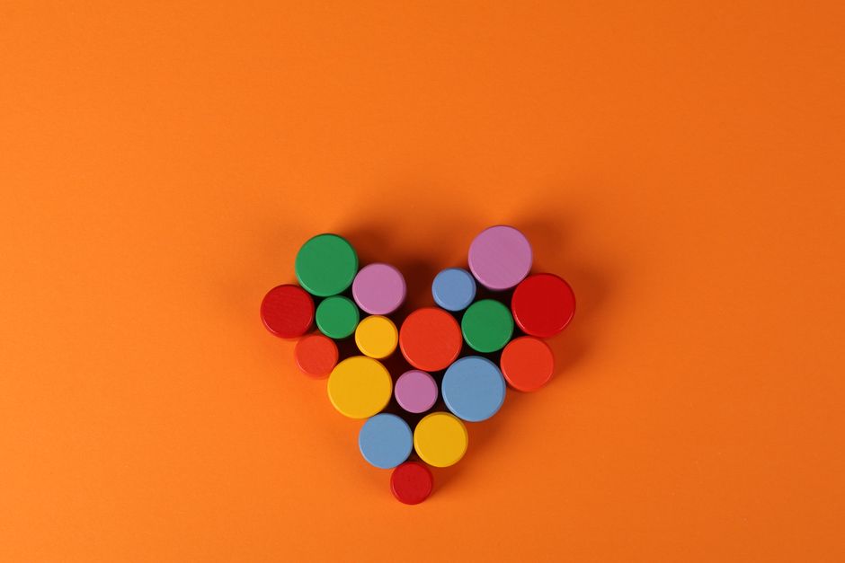 Vibrant circular shapes arranged in a heart on an orange background, perfect for creative and abstract concepts.