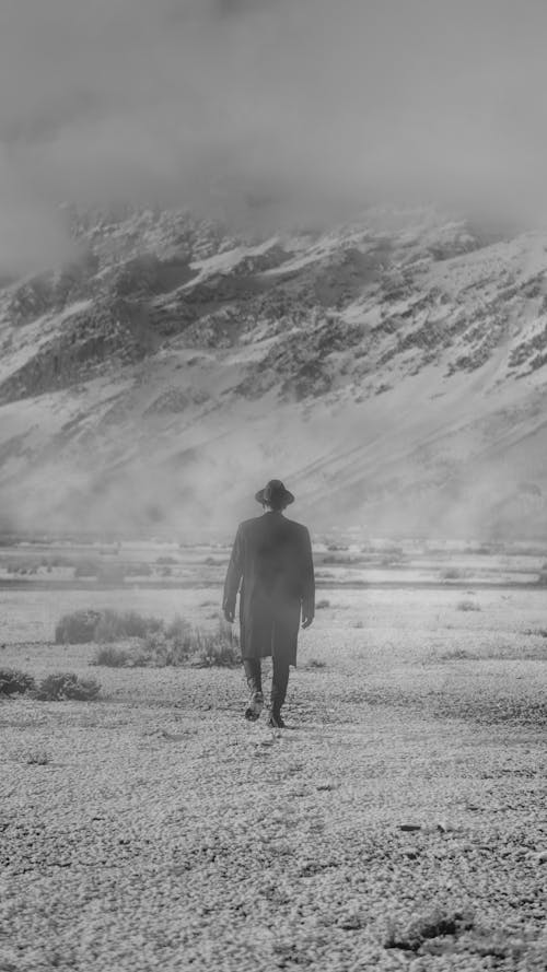 Grayscale Photo of a Man Walking on the Field