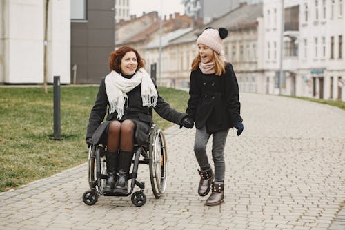 Woman in a Wheelchair Holding Hands with a Girl
