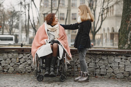 A Girl Talking to a Woman Sitting on a Wheelchair