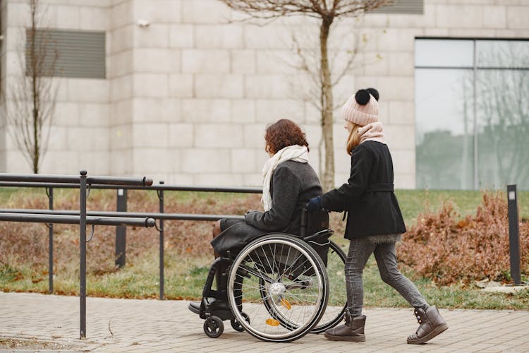 A Girl Pushing A Woman In A Wheelchair