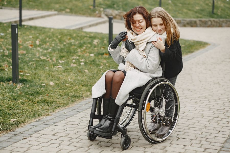 A girl embracing her mother, who uses a wheelchair