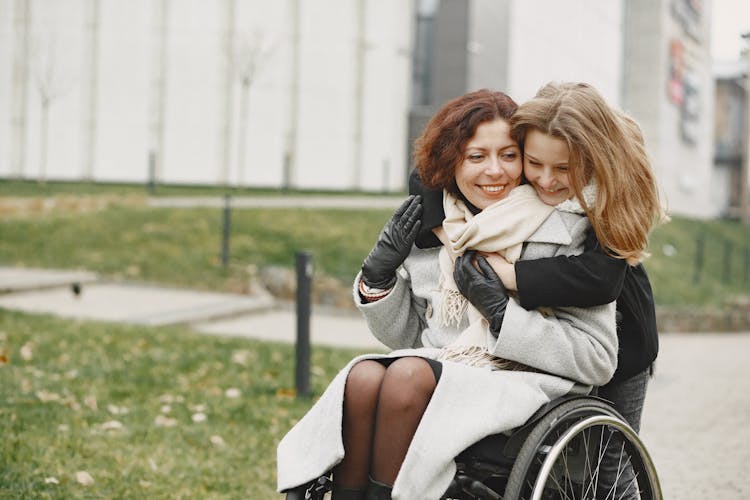 A Daughter Hugging Her Mother On Wheelchair