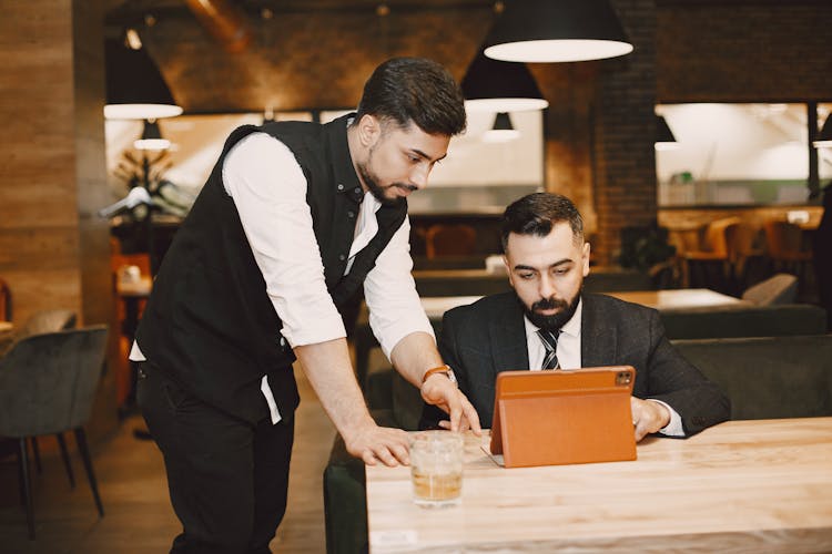 Two Men Looking At An Ipad In A Restaurant