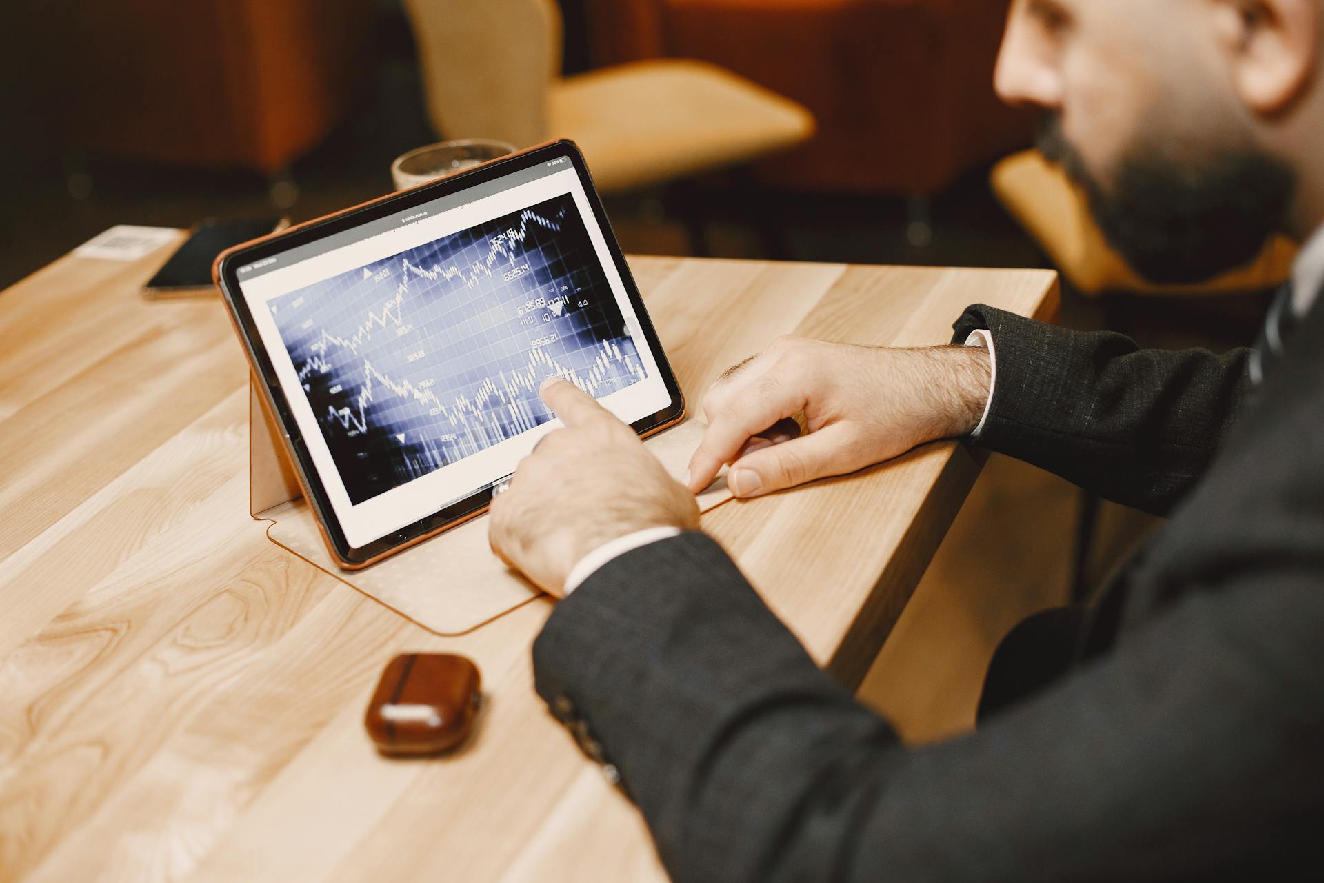 Business professional reviewing stock market data on a tablet in a modern office setting.