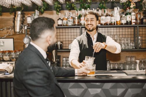 Free Friendly bartender mixing a cocktail for a customer at a modern bar. Stock Photo