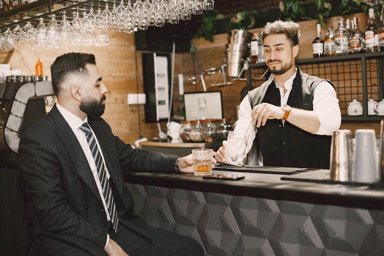 Bartender Serving A Drink To A Man In A Suit 