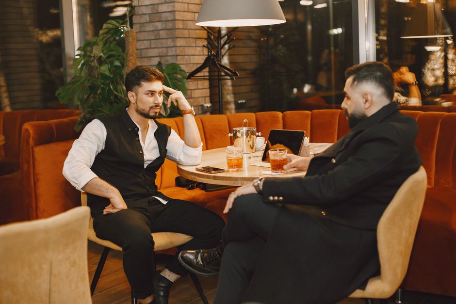 Two men enjoying cocktails in a warm, cozy lounge setting. Perfect for social and lifestyle themes. Two men enjoying cocktails in a warm, cozy lounge setting. Perfect for social and lifestyle themes.