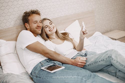 Free A Happy Couple Lying Down on a Bed Stock Photo