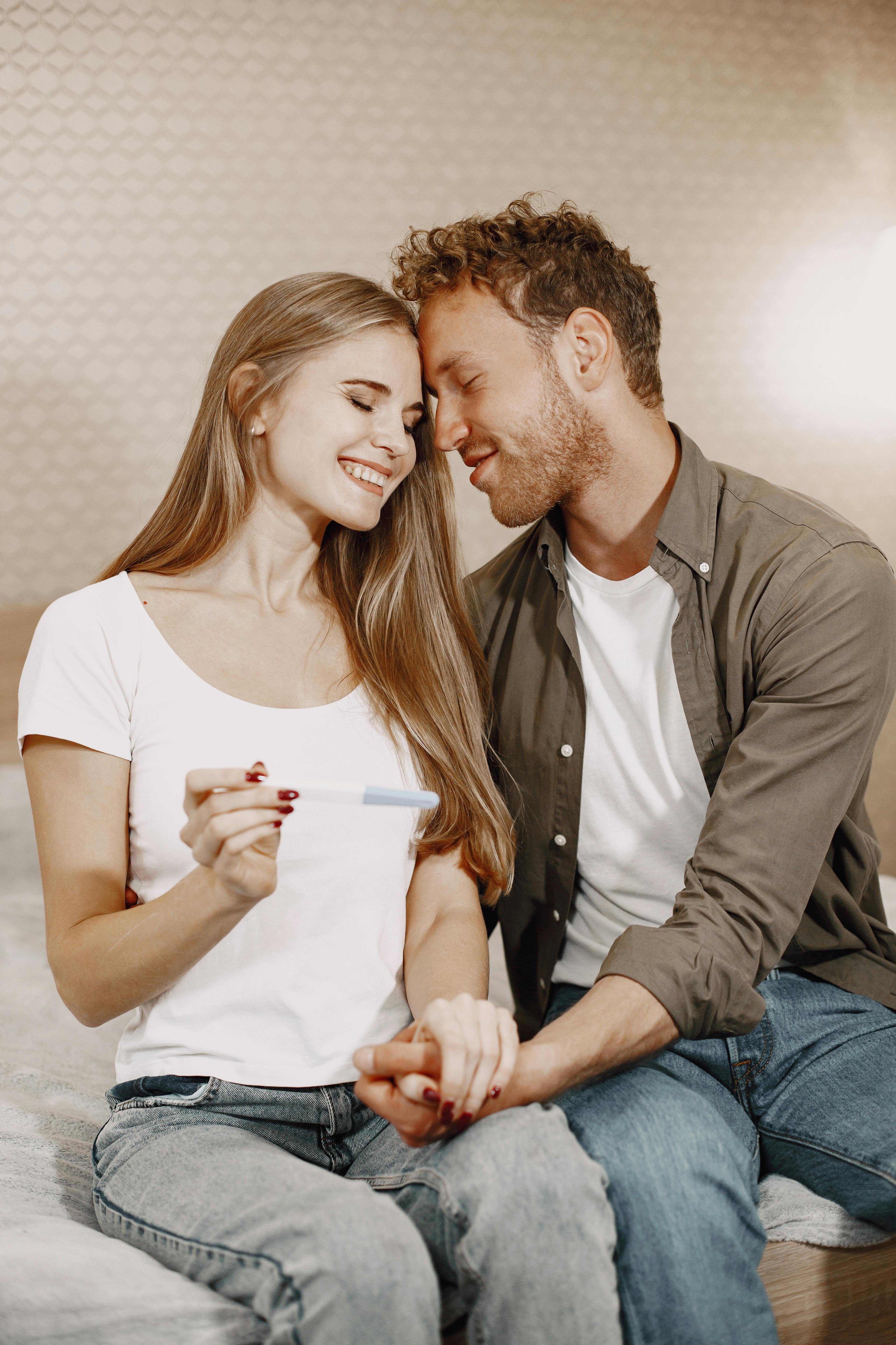 Happy couple indoors celebrating positive pregnancy news together, smiling with joy.