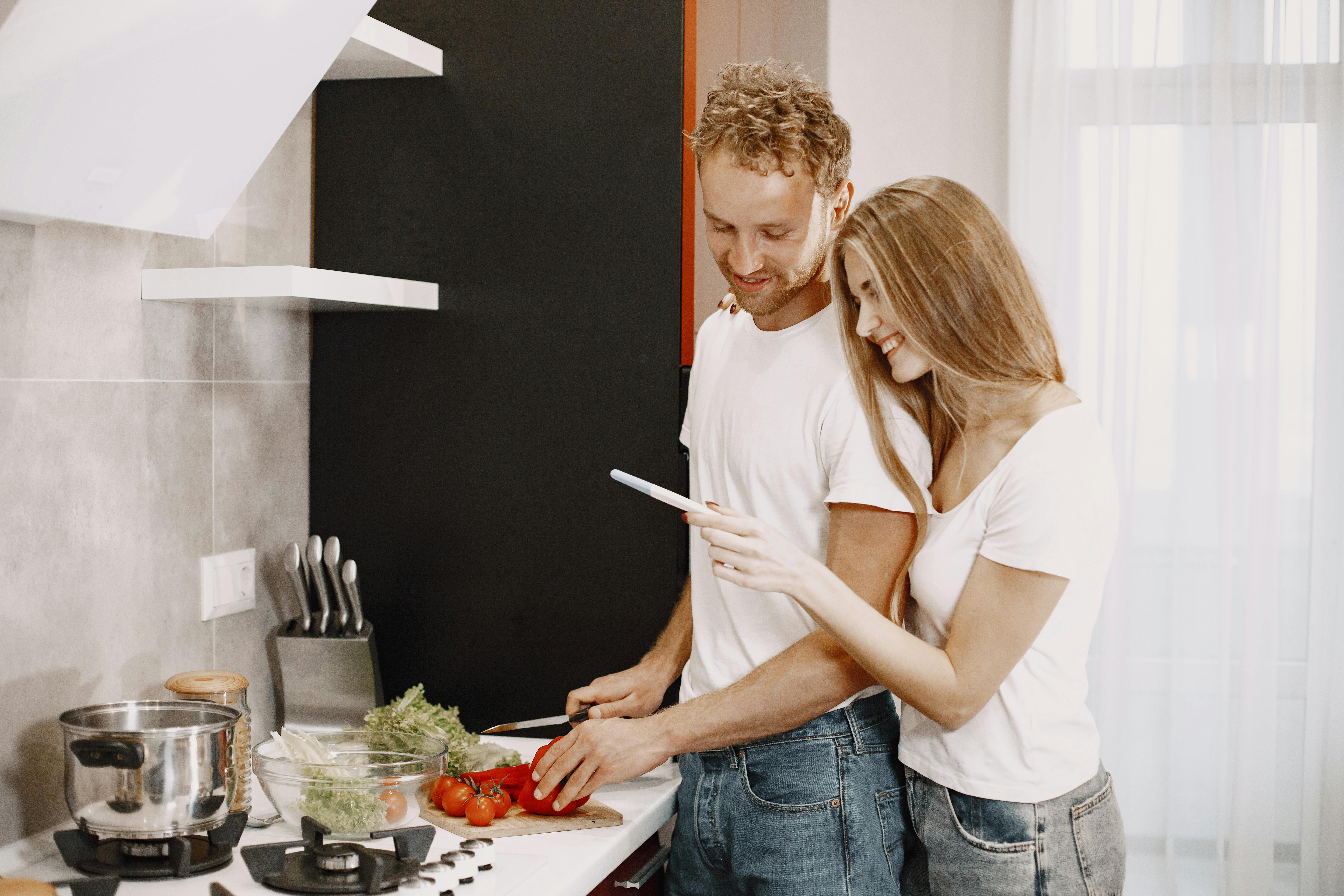 Couple happily preparing a healthy meal together in a modern kitchen setting.