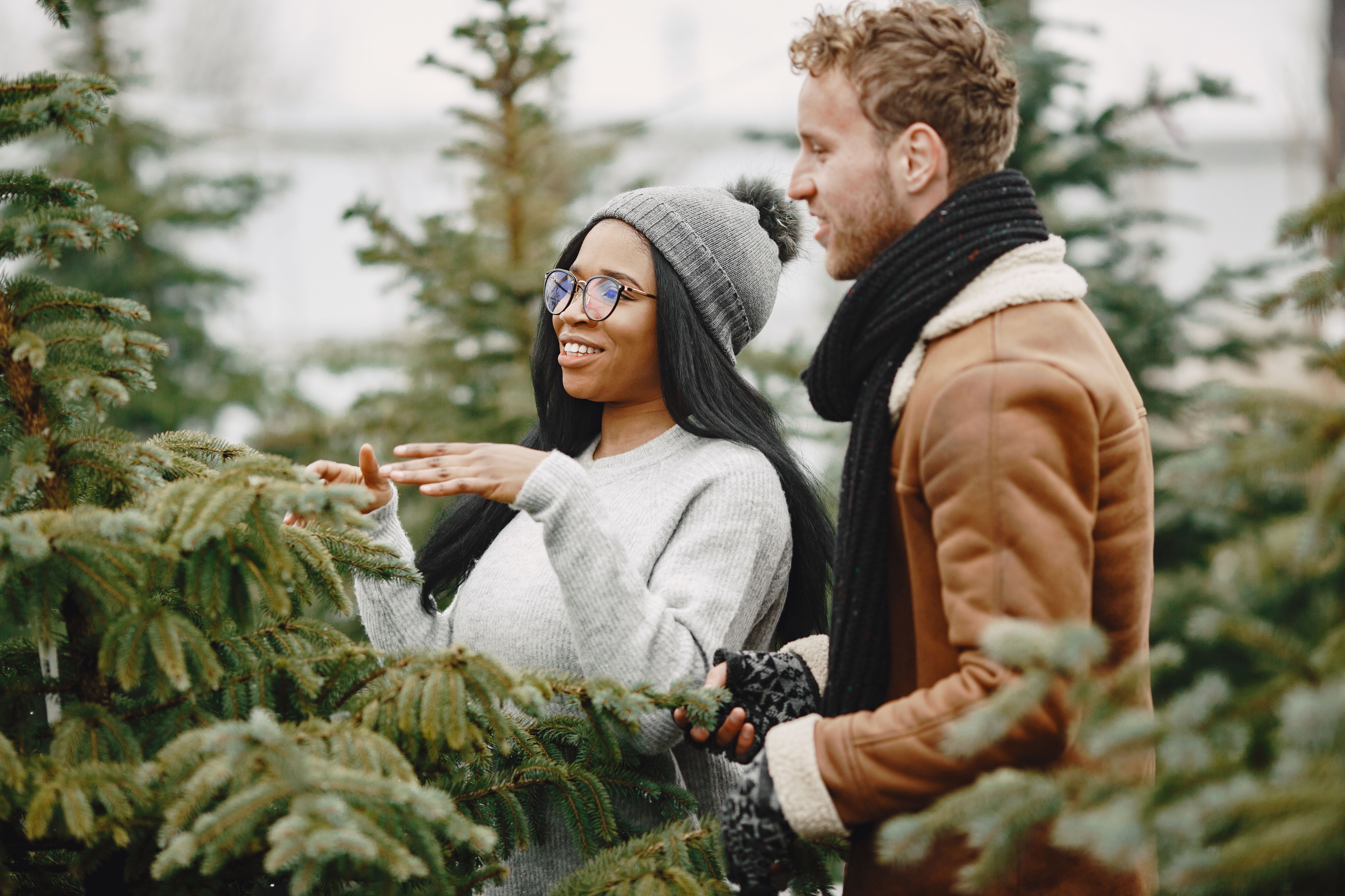 A joyful couple explores a winter landscape surrounded by evergreen trees. Captured outdoors.