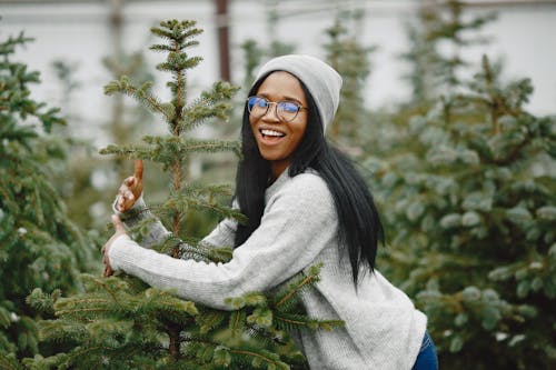 A Woman Wearing Gray Sweater and Gray Beanie Standing near the Christmas Tree