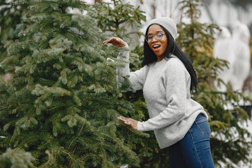 A Woman Wearing Gray Sweater and Gray Beanie Standing near the Christmas Tree