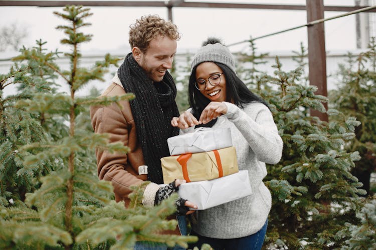 Couple With Pile Of Gifts Among Rows Of Fir Trees