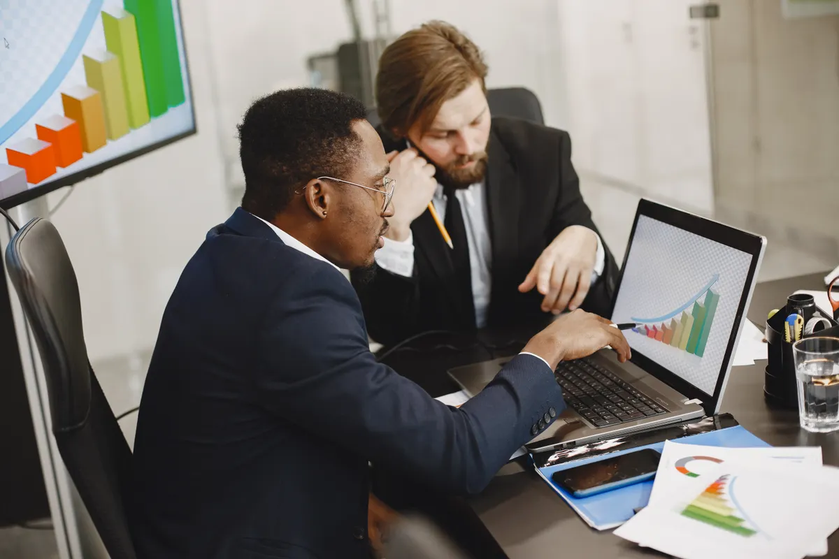 Two business professionals analyzing website SEO optimization performance on a laptop.