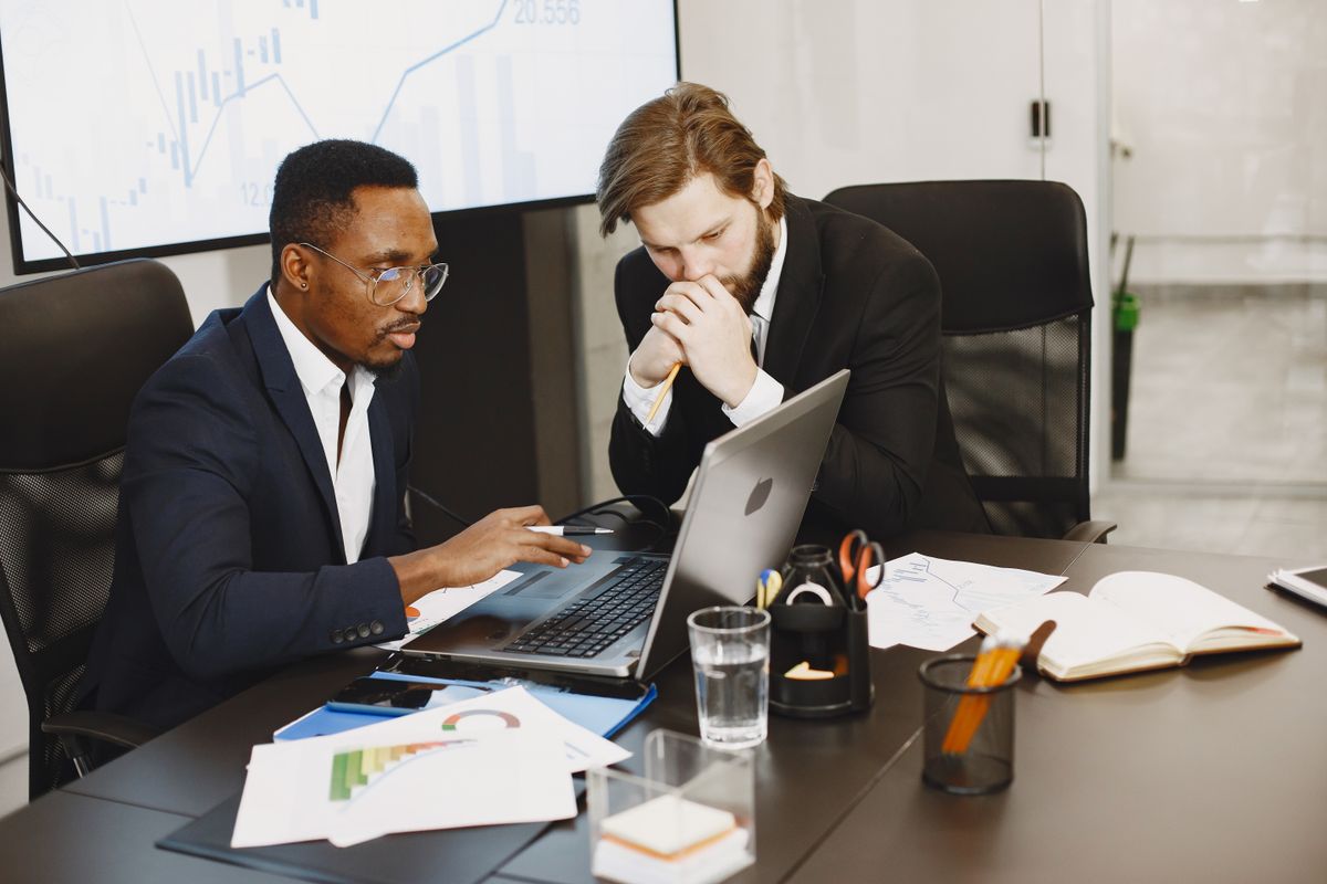 Two professionals reviewing charts and laptops together in a strategy meeting