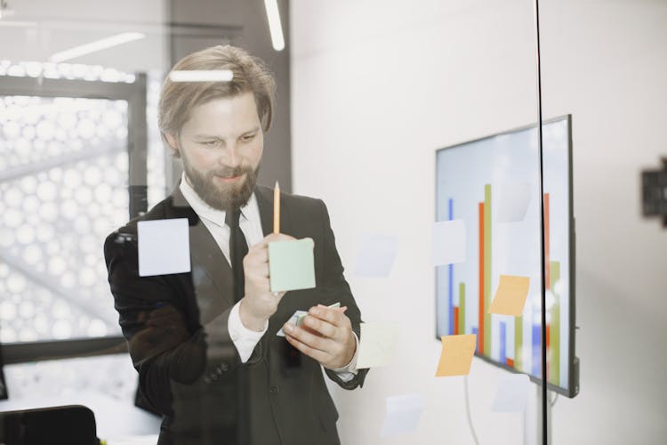 Man Brainstorming In Front Of Glass Wall