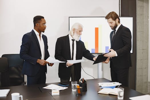 Three businessmen discussing documents in a conference setting with a presentation screen.