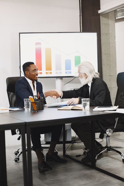 Photo by Gustavo Fring Two diverse businessmen in suits shaking hands over a desk in a modern office.