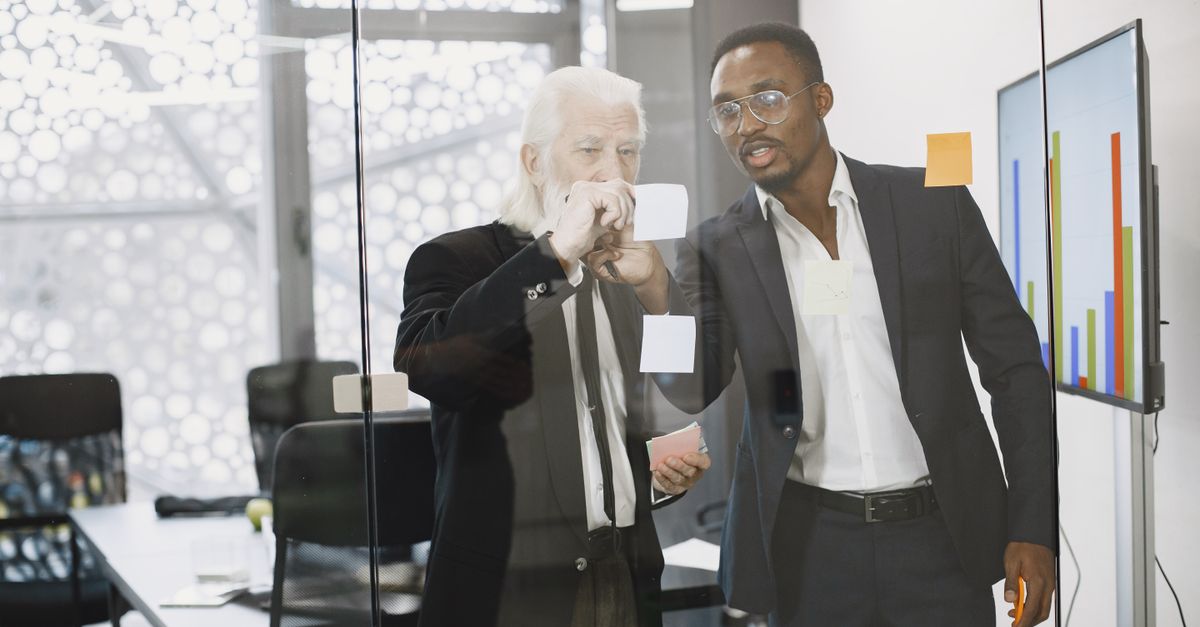 Men Putting Sticky Notes on Glass Wall · Free Stock Photo