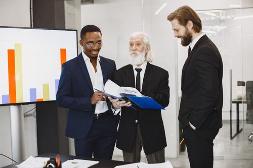 Free A diverse team of businessmen discussing reports in a modern office setting. Stock Photo
