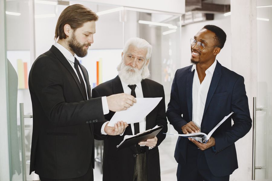Three business professionals discussing strategy documents in a modern office