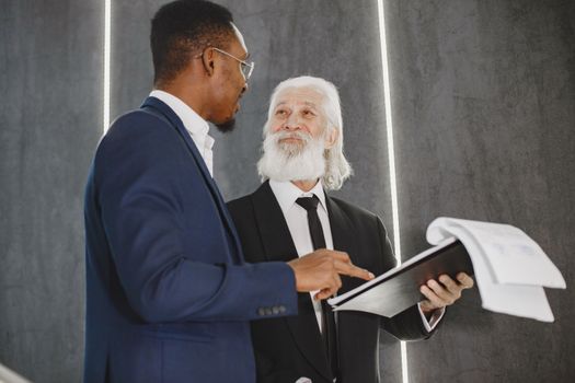 Two businessmen discussing documents in a modern office setting, highlighting professional diversity.
