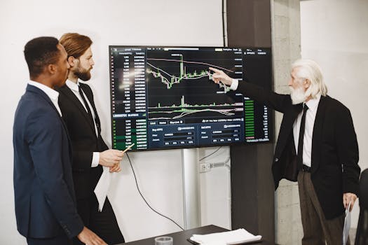 A diverse business team in a meeting analyzing stock market data on a screen.