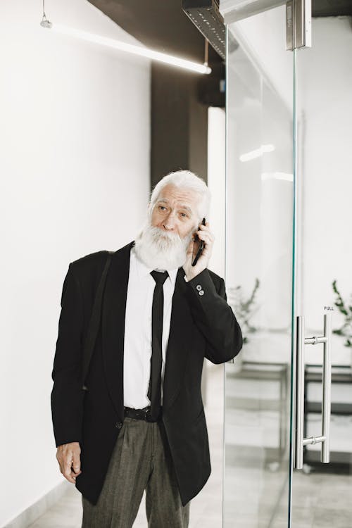 Free Elderly Man in a Black Suit Talking on His Cell Phone Stock Photo