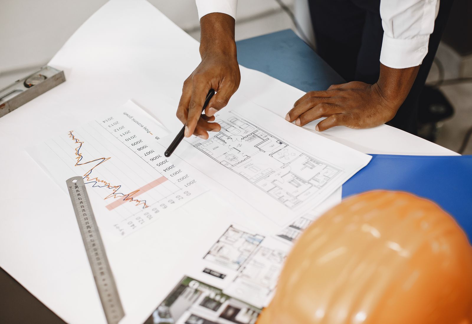 Mesa com planta baixa, gráficos e documentos para consultoria técnica