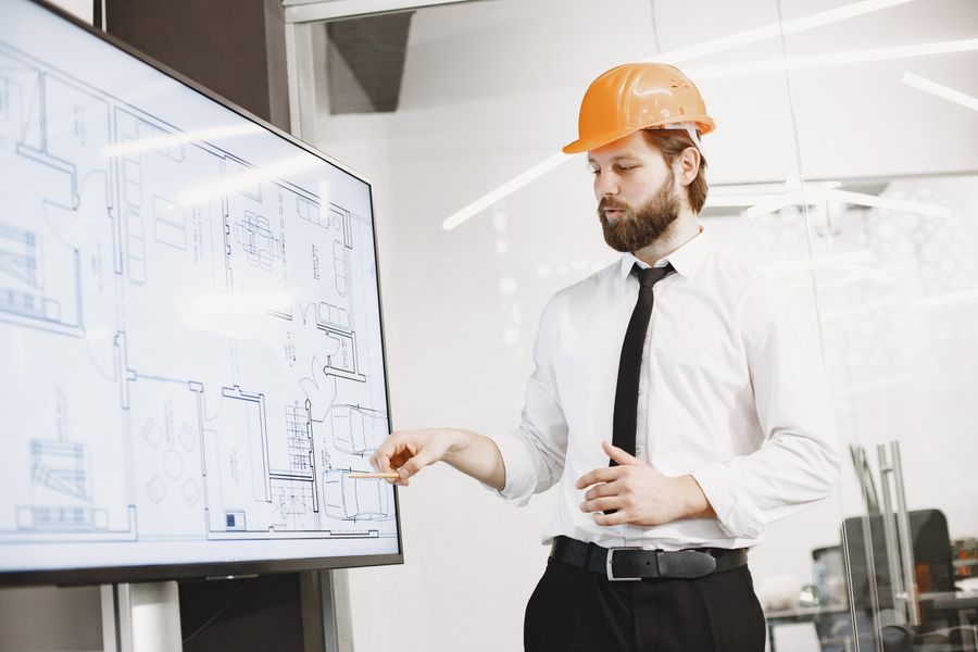 Project manager in safety helmet and hi-vis vest discussing plans with a colleague in business attire