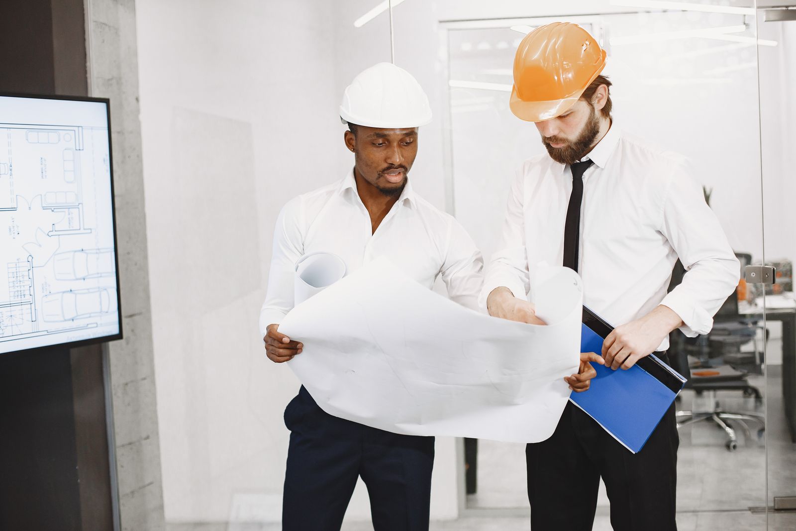 Engineers checking technical drawings against project documentation before production