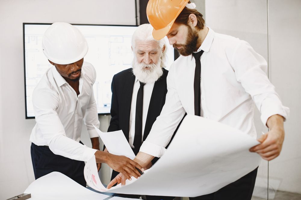 Three architects reviewing blueprints, Gustavo Fring on Pexels