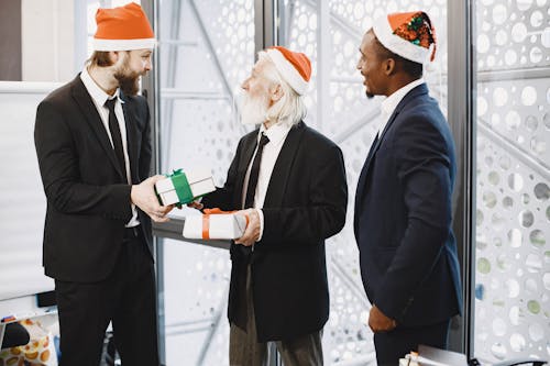 Free Businessmen in Santa Hats Exchanging Gifts Stock Photo