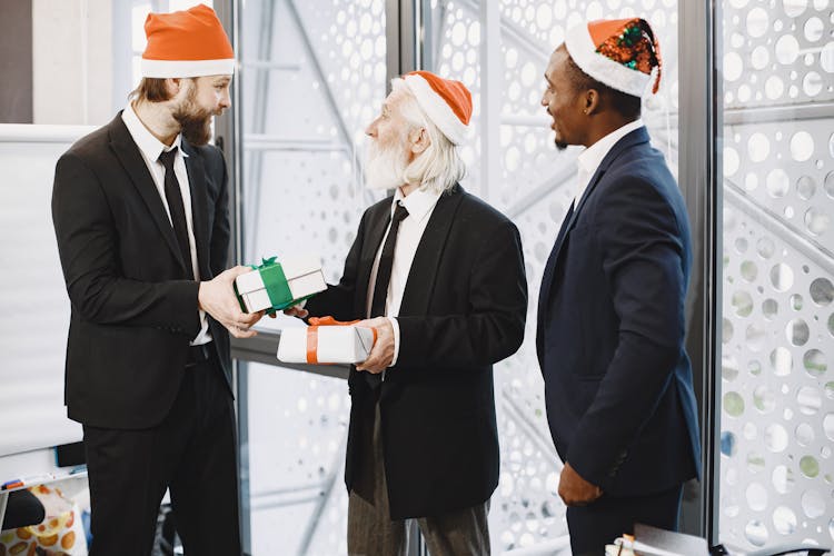 Businessmen In Santa Hats Exchanging Gifts