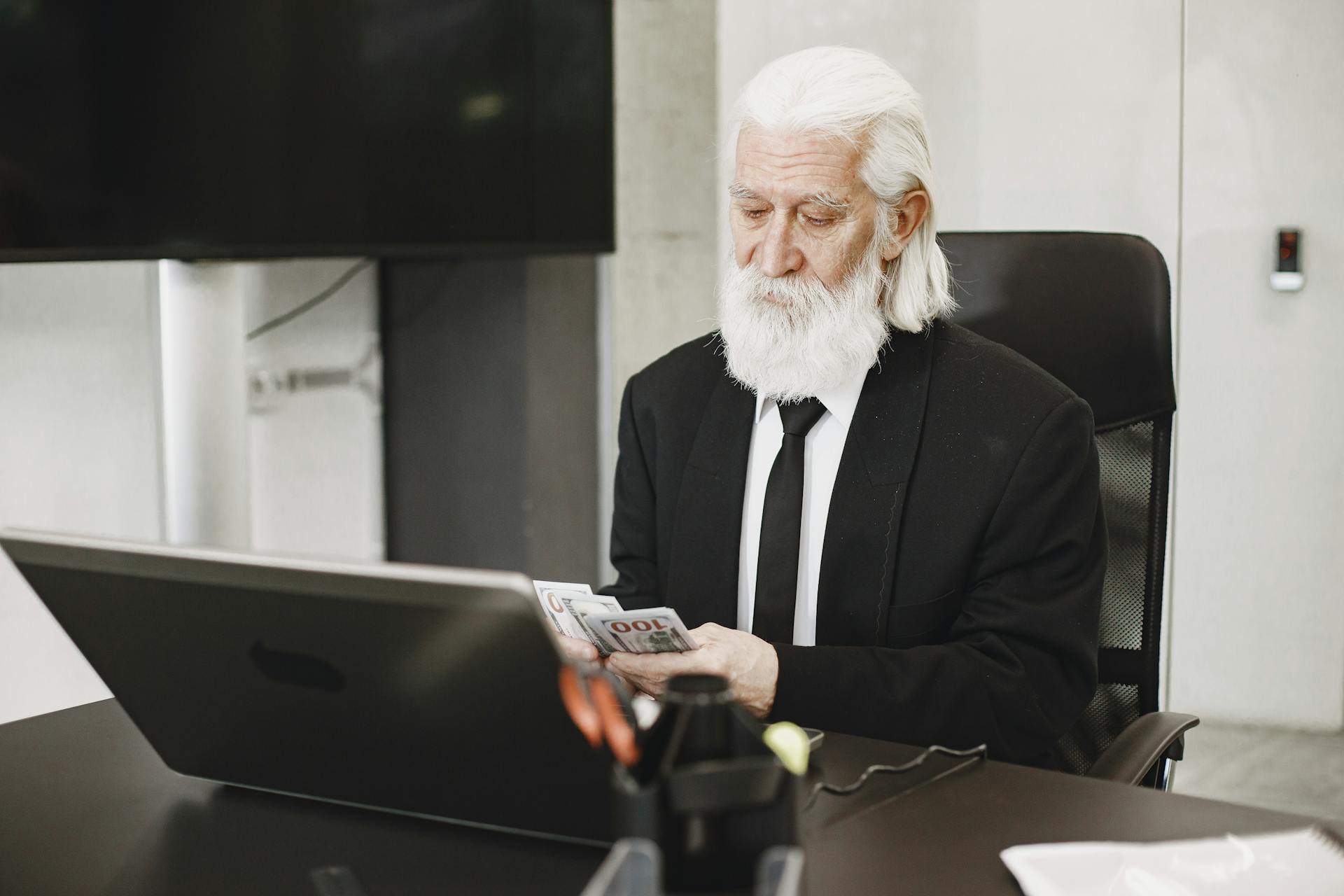 Elderly Man Counting Money in Office