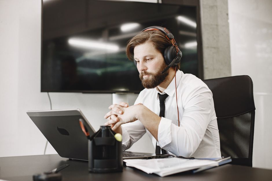 Hombre profesional enfocado trabajando de forma remota con auriculares en una oficina moderna.