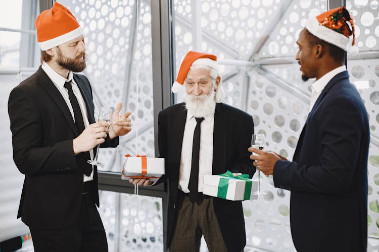 Businessmen In Santa Hats Exchanging Gifts