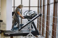 Woman in Gray Shirt and Gray Pants Sitting on Black Treadmill