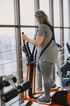 A plus size woman working out on an elliptical trainer, promoting active lifestyle and wellness indoors.