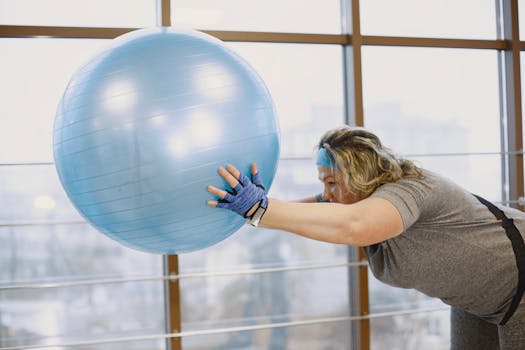 Woman practicing fitness using a blue exercise ball at the gym.